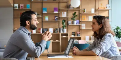 photo of two people talking over a laptop